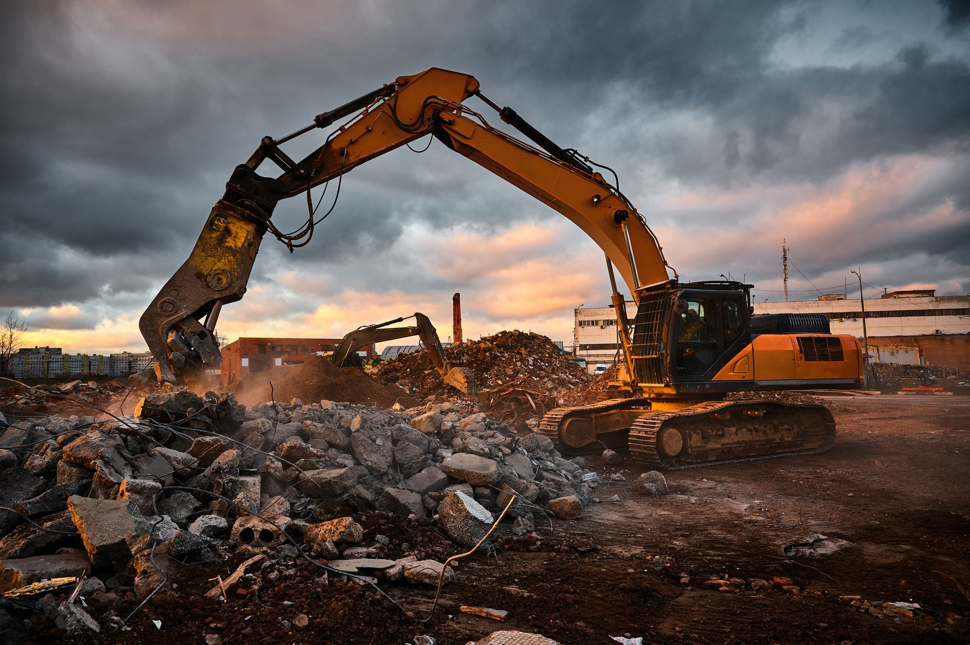 Modern crusher on excavator rigging dismantles concrete beam